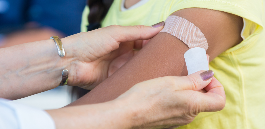 Healthcare professional applying band-aid to child's arm