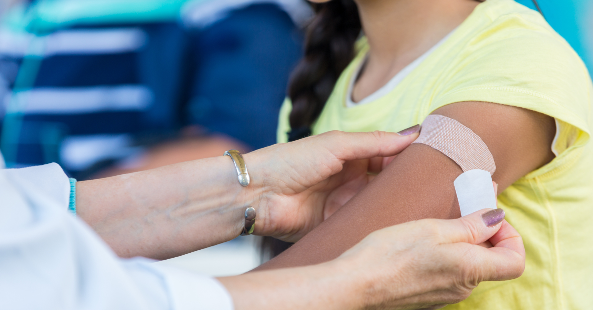 Healthcare professional applying band-aid to child's arm